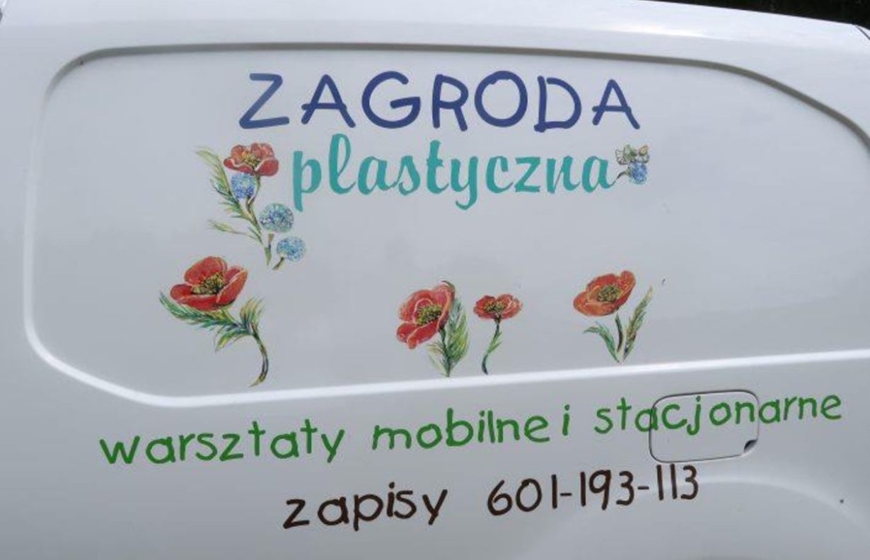 Na białym tle znajduje się kolorowy napis "ZAGRODA plastyczna" z rysunkami kwiatów. Poniżej widnieje tekst "warsztaty mobilne i stacjonarne zapisy 601-193-113".